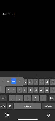 Text editor on an iOS device. The em dash button on the keyboard is highlighted.